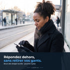 Femme qui écrit sur son téléphone à un arrêt de tram avec les gants Light R